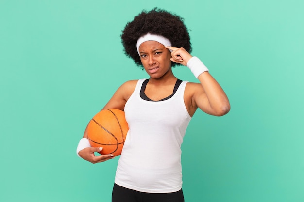 Donna afro che si sente confusa e perplessa, mostrando che sei pazzo, pazzo o fuori di testa. concetto di basket