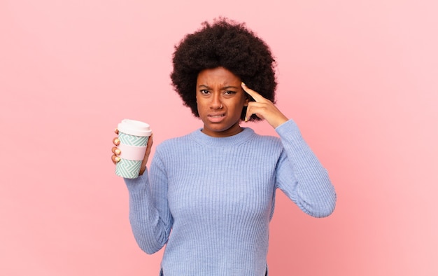 Donna afro che si sente confusa e perplessa, mostrando che sei pazzo, pazzo o fuori di testa. concetto di caffè