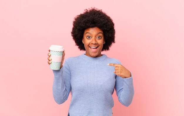 Donna afro che si sente felice, sorpresa e orgogliosa, indicando se stessa con uno sguardo eccitato e stupito. concetto di caffè