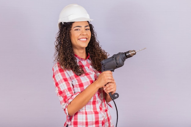 Donna afro in possesso di un trapano elettrico su sfondo bianco.