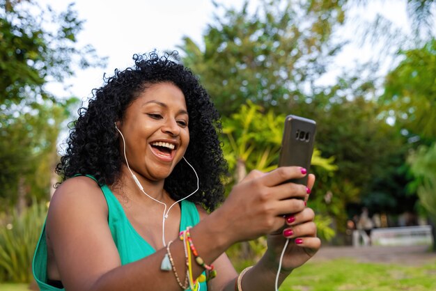 Donna afro latina con cuffie e cellulare