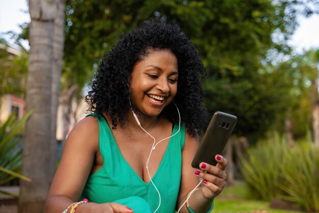 Donna afro latina con cuffie e cellulare