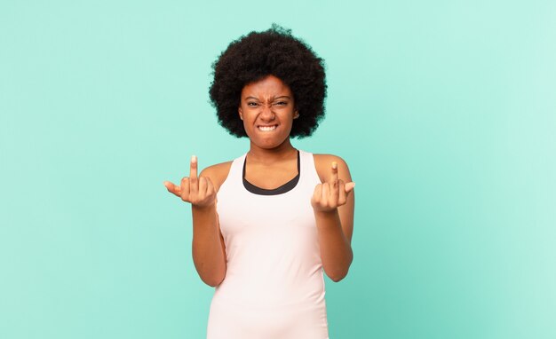 Donna afro nera che indossa abiti da fitness contro il muro isolato