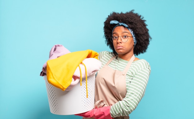 Donna afro nera che scrolla le spalle, sentendosi confusa e incerta, dubitando con le braccia incrociate e lo sguardo perplesso. concetto di pulizie .. concetto di famiglia