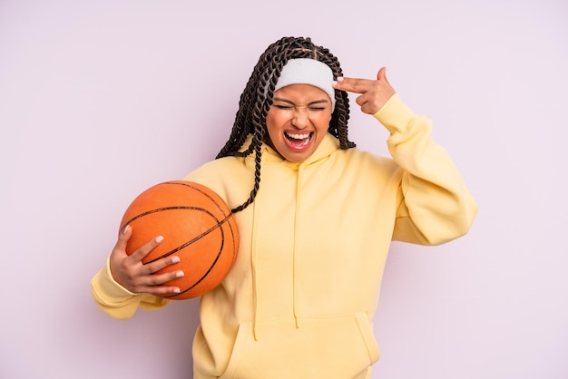 Donna afro nera che sembra gesto suicida infelice e stressato facendo segno di pistola concetto di basket