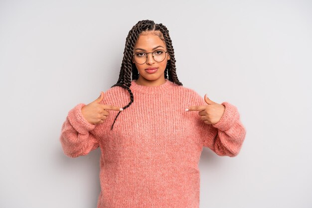 Donna afro nera che sembra orgogliosa, positiva e casual che punta al petto con entrambe le mani