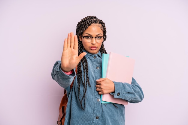 Donna afro nera che sembra seria mostrando il palmo aperto facendo gesto di arresto concetto di studente universitario