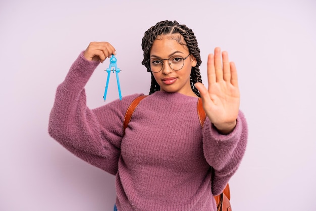 Donna afro nera che sembra seria mostrando il palmo aperto facendo il gesto di arresto misura il concetto di studente bussola