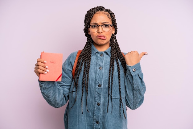 Donna afro nera che sembra stupita nell'incredulità del calendario degli studenti o del concetto di agenda