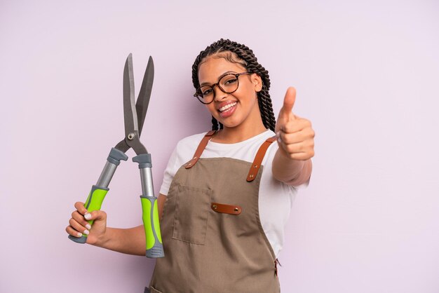 Donna afro nera che si sente orgogliosa, sorride positivamente con i pollici in su. concetto di giardiniere o agricoltore