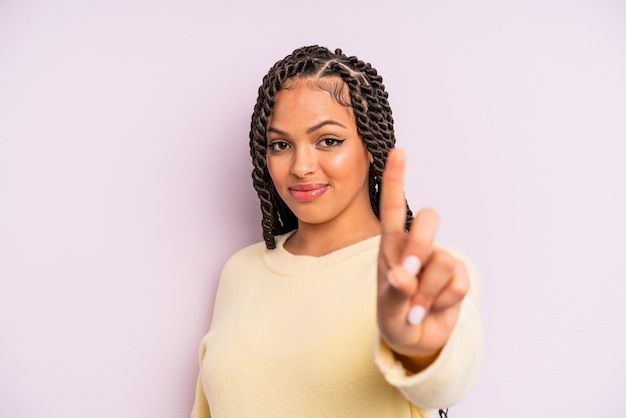 Donna afro nera che sorride con orgoglio e sicurezza facendo il numero uno