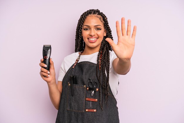 Donna afro nera che sorride e che sembra amichevole, mostrando il numero cinque. concetto di negozio di barbiere