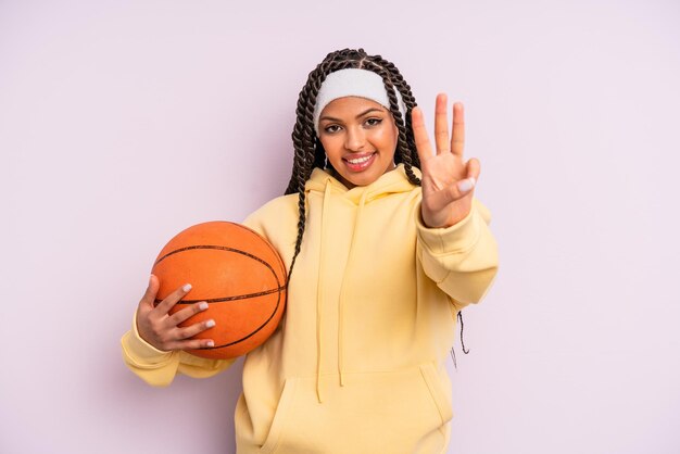 donna afro nera che sorride e sembra amichevole, mostrando il numero tre. concetto di basket