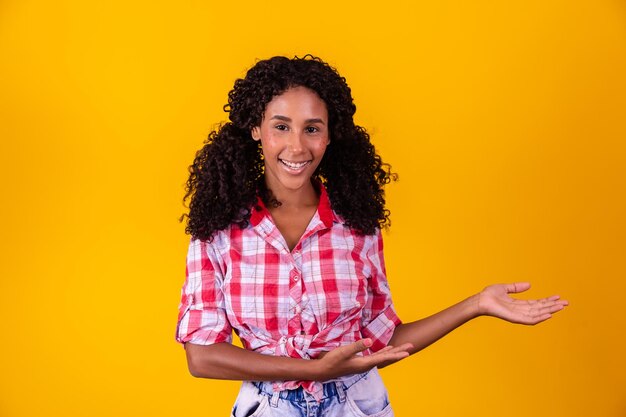 Donna afro vestita con un vestito da festa junina che indica lo spazio libero laterale per il testo