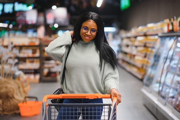 Donna afroamericana al supermercato con il carrello.