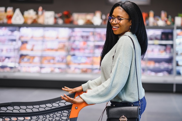 Donna afroamericana al supermercato con il carrello.