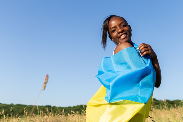 Donna afroamericana avvolta nel simbolo nazionale della bandiera blu gialla ucraina dell'Ucraina