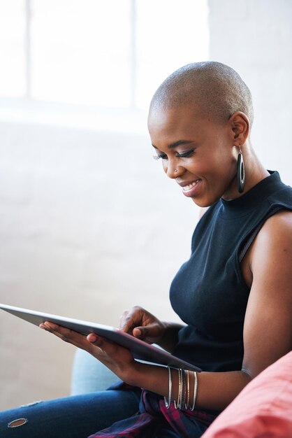 Donna afroamericana calva che utilizza il computer tablet digitale a casa