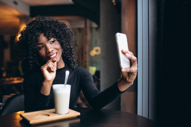 Donna afroamericana che fa selfie e che beve caffè in caffè