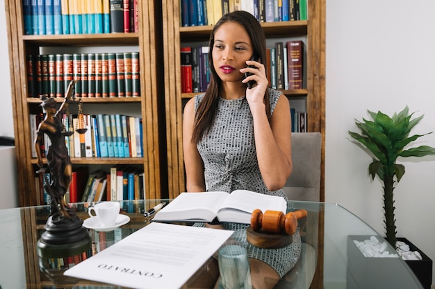 Donna afroamericana che parla sullo smartphone al tavolo in ufficio