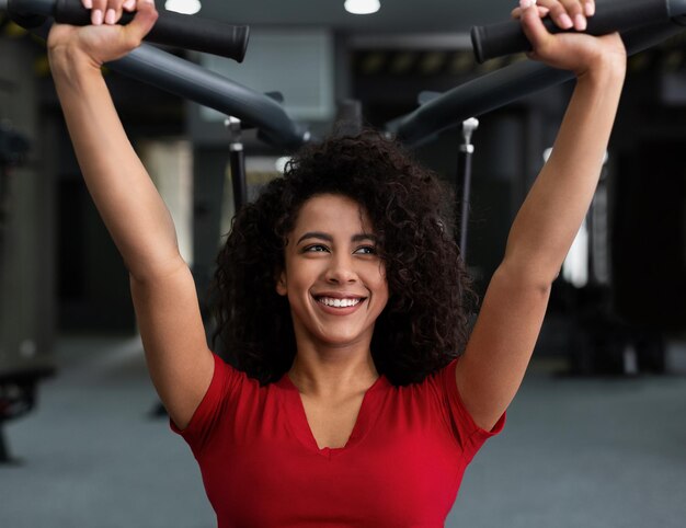 Donna afroamericana che si esercita in palestra, allenamento bicipiti sulla macchina