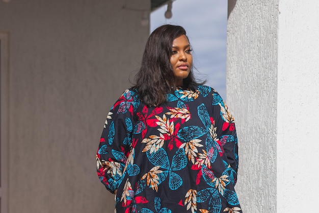 Donna afroamericana che si rilassa e si gode il sole stando in piedi sulla terrazza o sul balcone alla luce del sole