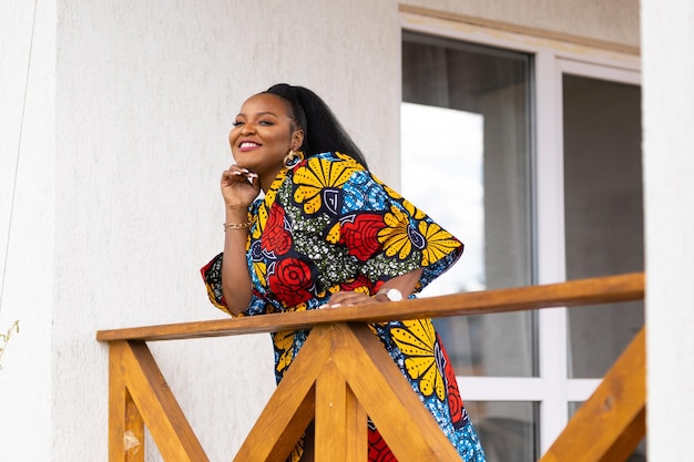 Donna afroamericana che si rilassa e si gode il sole stando in piedi sulla terrazza o sul balcone alla luce del sole