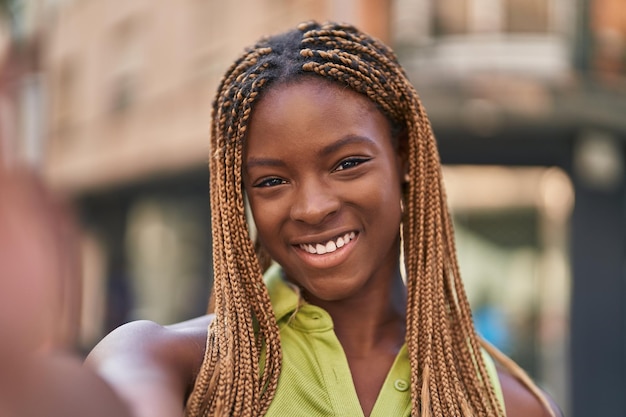 Donna afroamericana che sorride sicura facendo selfie con la macchina fotografica in strada