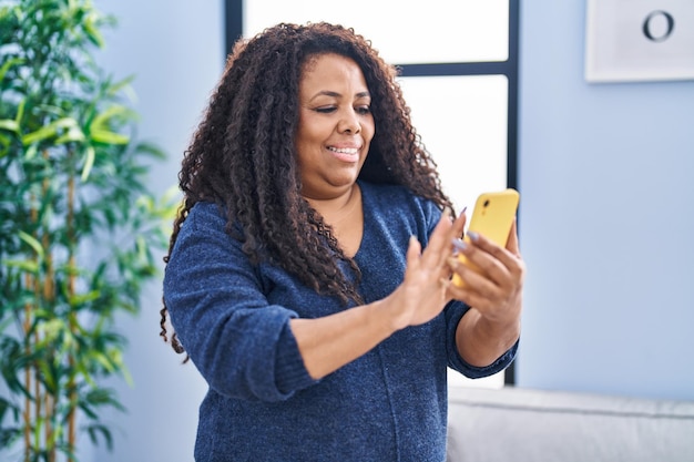 Donna afroamericana che usa lo smartphone in piedi a casa