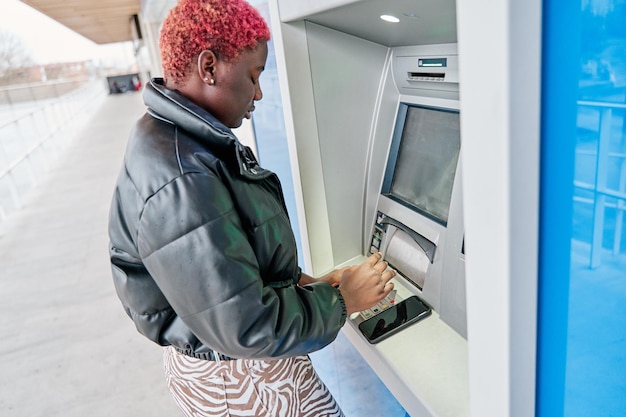 Donna afroamericana che utilizza un bancomat