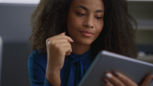 Donna afroamericana che utilizza un dispositivo tablet alla ricerca di dati in ufficio Ritratto di imprenditore concentrato che lavora su scheda digitale Bella ceo femminile che naviga navigando in internet Concetto di lavoro remoto