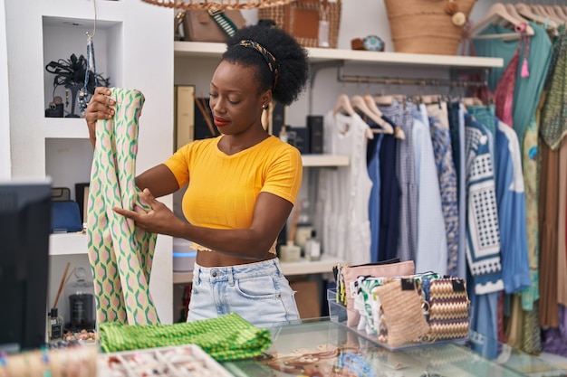 Donna afroamericana commessa vestiti pieghevoli che lavorano al negozio di abbigliamento