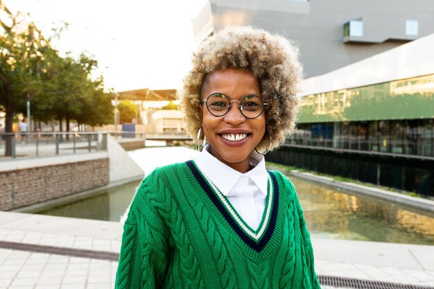 Donna afroamericana con acconciatura afro e maglione verde in città Guardando la fotocamera Copia spazio