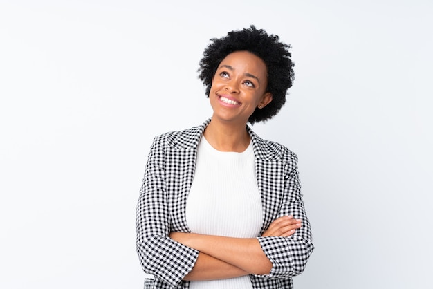 Donna afroamericana con blazer su bianco isolato che osserva in su mentre sorride