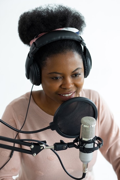Donna afroamericana con cuffie e microfono che registra un podcast in uno studio di registrazione
