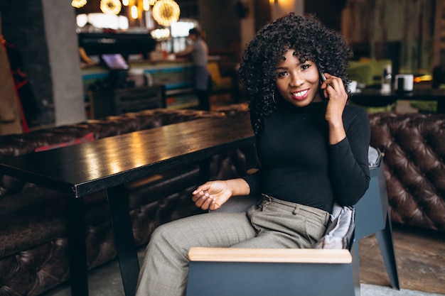 Donna afroamericana con il telefono in caffè