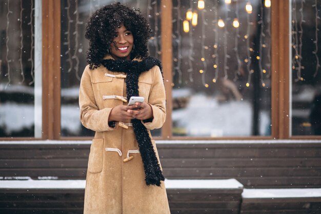 Donna afroamericana con il telefono in inverno