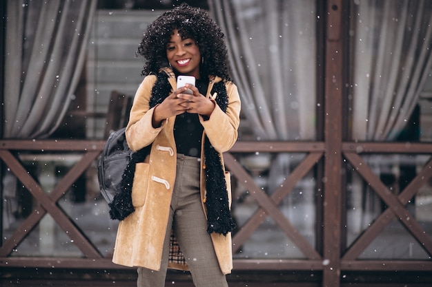 Donna afroamericana con il telefono in inverno