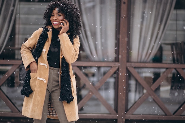 Donna afroamericana con il telefono in inverno