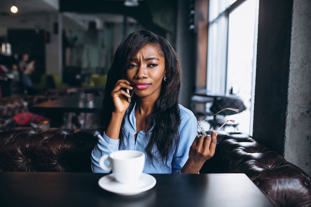 Donna afroamericana con il telefono in un caffè