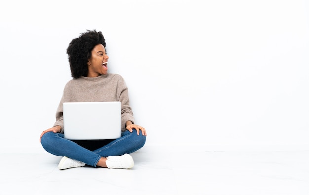 Donna afroamericana con un laptop seduto sul pavimento