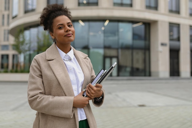 Donna afroamericana d'affari con un laptop in mano sullo sfondo di un ufficio