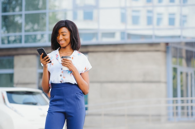 Donna afroamericana di affari che comunica su un telefono cellulare all'edificio per uffici