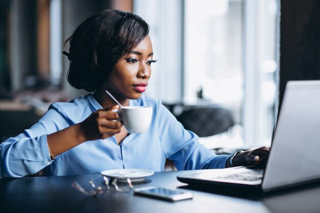 Donna afroamericana di affari con il computer portatile in un caffè