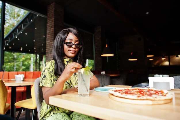 Donna afroamericana di fascino che mangia pizza al ristorante.