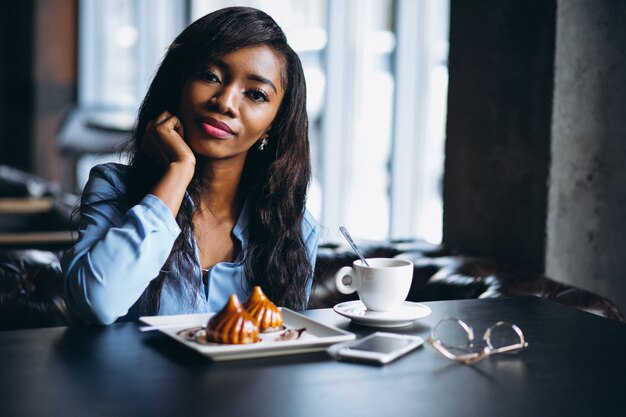 Donna afroamericana in un caffè che mangia dessert