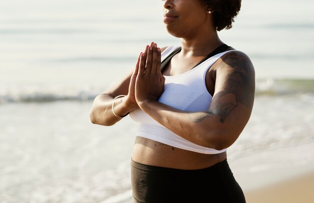 Donna afroamericana praticando yoga in spiaggia