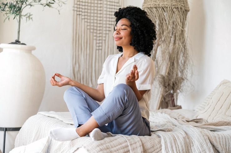 Foto donna afroamericana rilassata che fa esercizi di yoga sul letto.