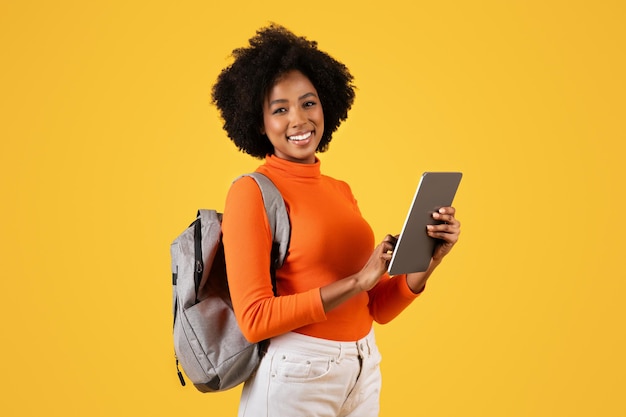 Donna afroamericana sicura di sé con i capelli ricci sorridendo e tenendo in mano un tablet digitale