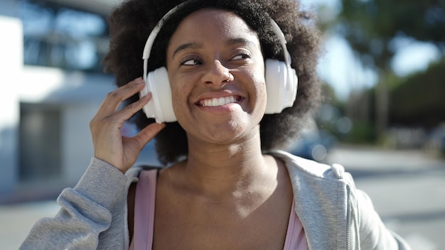 Donna afroamericana sorridente fiducioso ascoltando musica in strada